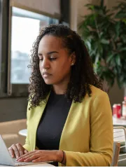 Une femme en blazer jaune travaillant sur son ordinateur portable